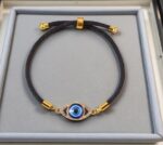 black adjustable bracelet with a blue evil eye  charm set in a gold-tone frame - Image 6