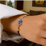 black adjustable bracelet with a blue evil eye  charm set in a gold-tone frame - Image 2